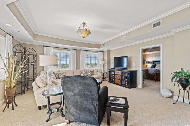 Carpeted living area featuring a tray ceiling and ornamental molding | Image 10