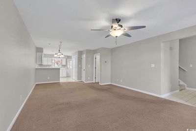 Unfurnished living room featuring a textured ceiling, light colored carpet, and ceiling fan with notable chandelier | Image 3