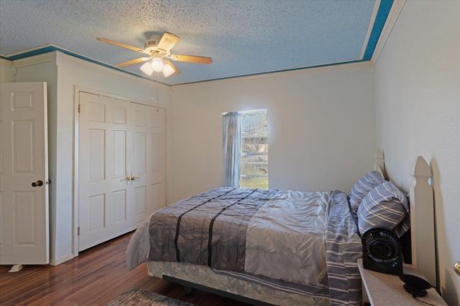 Bedroom with dark hardwood / wood-style flooring, ceiling fan, crown molding, and a textured ceiling | Image 20