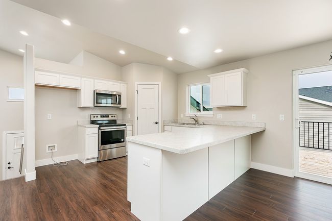 Kitchen with light countertops, vaulted ceiling, a peninsula, stainless steel appliances, and a sink | Image 7