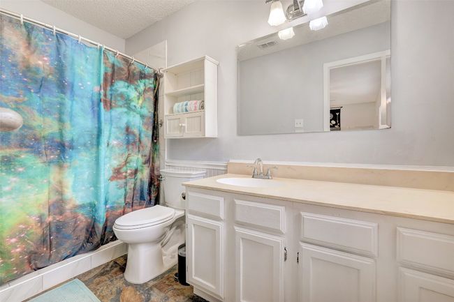 Full bath with toilet, vanity, a textured ceiling, and curtained shower | Image 26