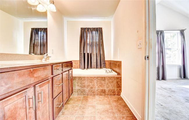Bathroom featuring a bath, vanity with double sinks, and tile flooring | Image 17