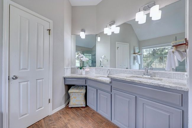 Full bathroom featuring wood finished floors, vaulted ceiling, a shower stall, and double vanity | Image 23