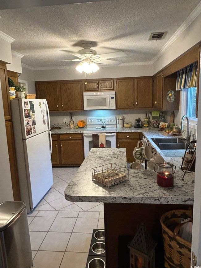 Kitchen with white appliances, ornamental molding, ceiling fan, a textured ceiling, and light tile patterned floors | Image 5