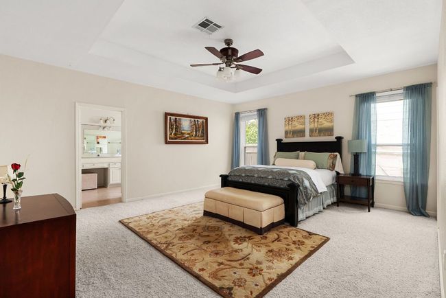 Bedroom featuring a tray ceiling, baseboards, carpet, and visible vents | Image 17
