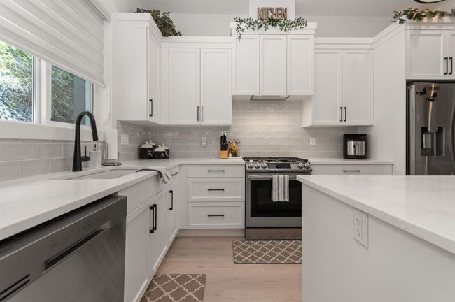 Kitchen featuring stainless steel appliances, a sink, and white cabinets | Image 12