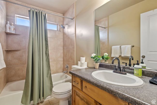 Full bathroom featuring toilet, tile patterned floors, shower / bathtub combination with curtain, and vanity | Image 20