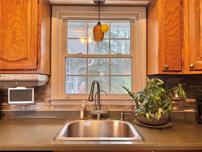 Kitchen with pendant lighting, brown cabinets, a sink, and decorative backsplash | Image 8