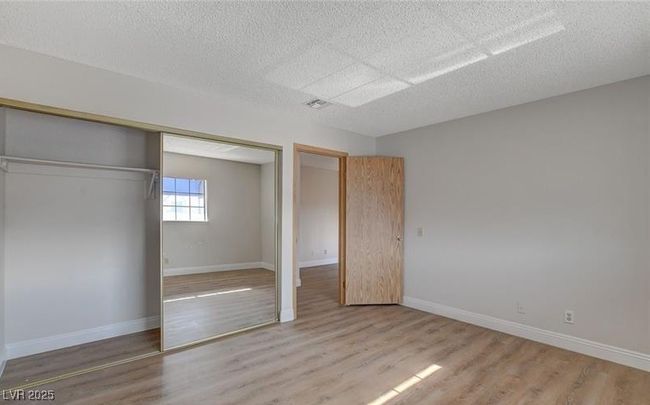 Unfurnished bedroom featuring a closet, wood finished floors, a textured ceiling, and baseboards | Image 12