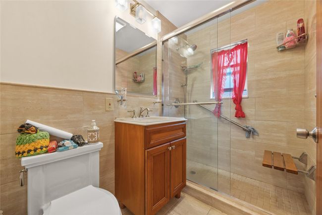 Full bath with vanity, tile walls, a stall shower, and tile patterned flooring | Image 16