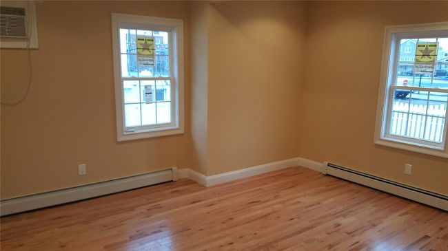 Unfurnished room featuring a wall mounted AC, a baseboard radiator, and light hardwood / wood-style flooring | Image 4