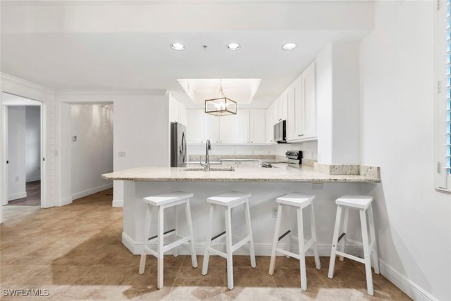 Kitchen featuring appliances with stainless steel finishes, sink, kitchen peninsula, decorative light fixtures, and white cabinets | Image 30