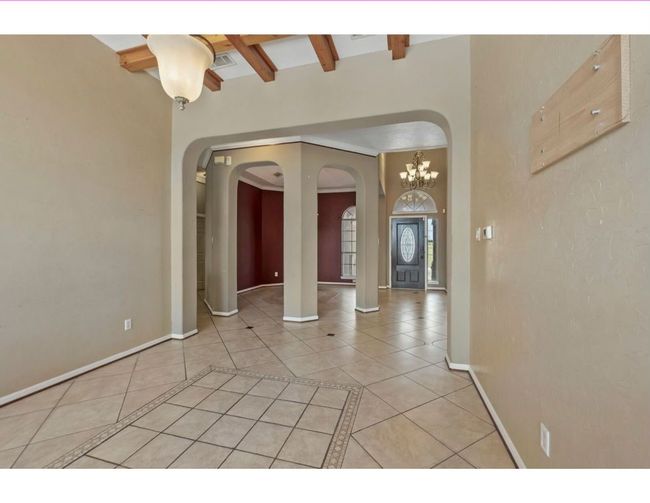 Unfurnished room with light tile patterned floors, beam ceiling, and inlaid floor details | Image 6