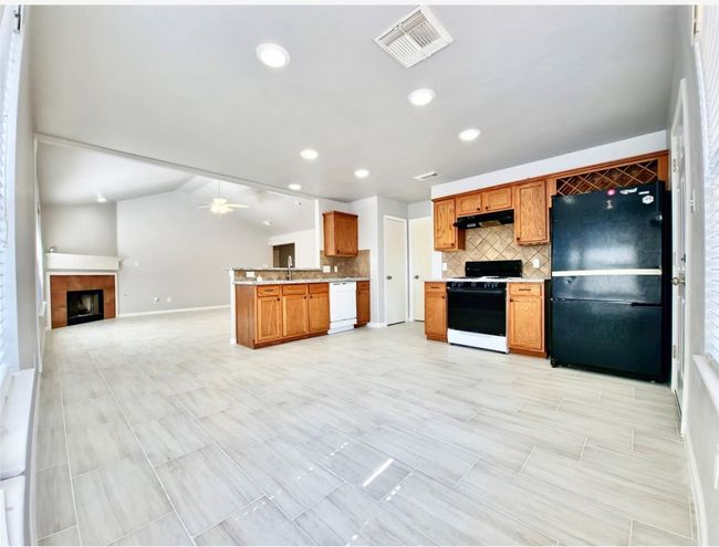 Kitchen with range with gas stovetop, freestanding refrigerator, dishwasher, under cabinet range hood, and decorative backsplash | Image 8