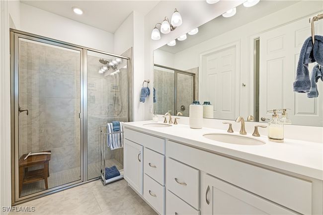 Bathroom with double vanity, a stall shower, and tile patterned flooring | Image 19