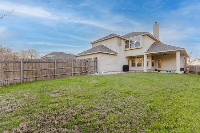 Rear view of house featuring a lawn, a fenced backyard, a shingled roof, ceiling fan, and a chimney | Image 39