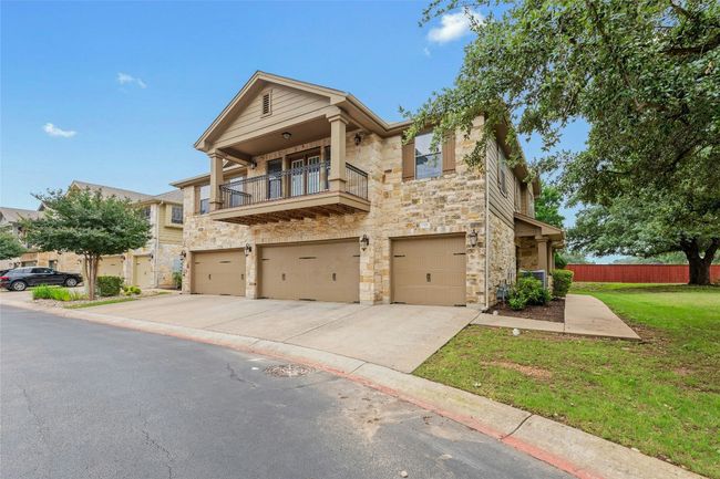 View of property featuring stone siding, a balcony, a garage, and concrete driveway | Image 4