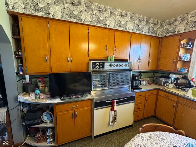 kitchen with wallpapered walls, oven, brown cabinetry, and open shelves | Image 15