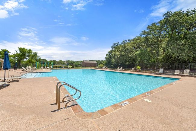 Community pool featuring a patio area and view of scattered trees | Image 34