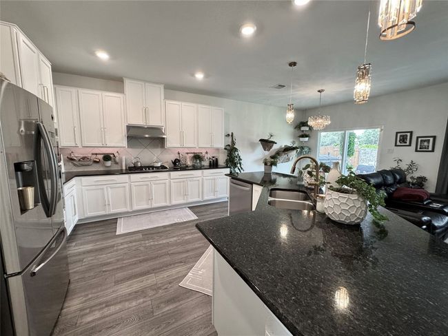 Kitchen with appliances with stainless steel finishes, a chandelier, under cabinet range hood, dark wood-style flooring, and backsplash | Image 11