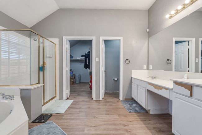 Full bath featuring a stall shower, vanity, a bath, a spacious closet, and wood finished floors | Image 29