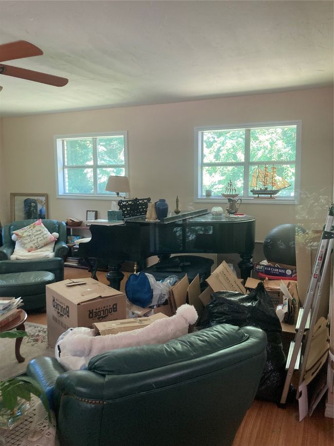 other half of Living room with wood burning stove and wood finished floors, ceiling fan, and plenty of natural light excuse the boxes owner is packing | Image 21