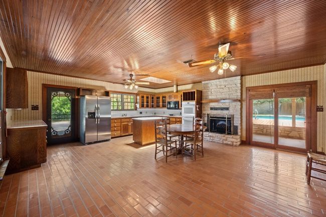 Kitchen with stainless steel fridge, ceiling fan, light countertops, microwave, and wooden ceiling | Image 10