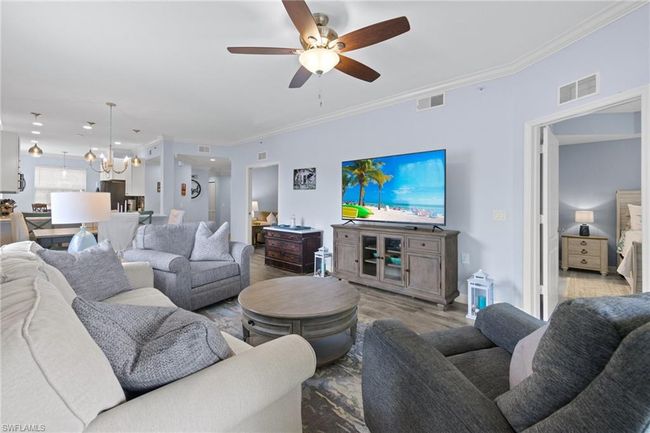 Living room with crown molding, ceiling fan with notable chandelier, and light wood-type lvp flooring | Image 12