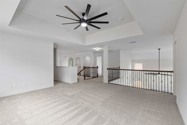 Empty room featuring baseboards, a raised ceiling, a ceiling fan, and carpet flooring | Image 24