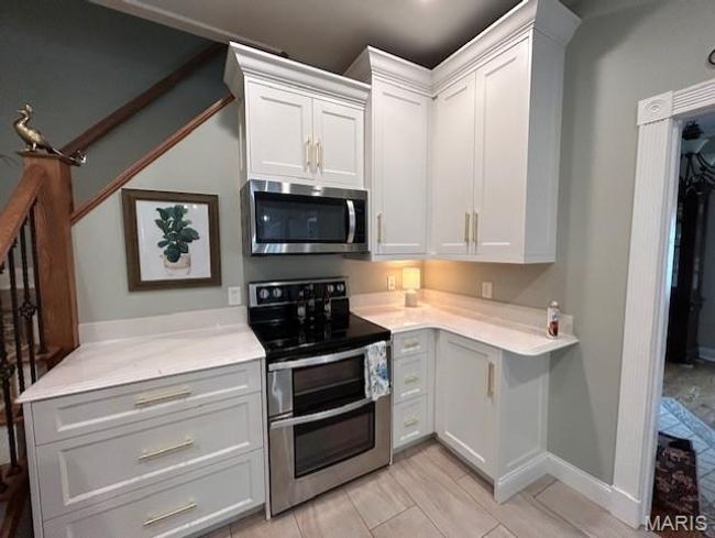 Kitchen with stainless steel appliances, light countertops, and white cabinets | Image 10