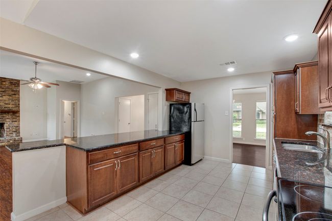 Kitchen with visible vents, a ceiling fan, freestanding refrigerator, light tile patterned flooring, and a sink | Image 5