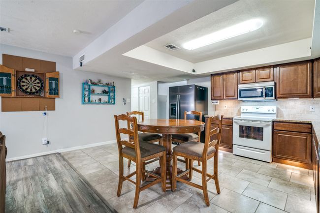 Kitchen with stainless steel appliances, brown cabinetry, tasteful backsplash, and light countertops | Image 12