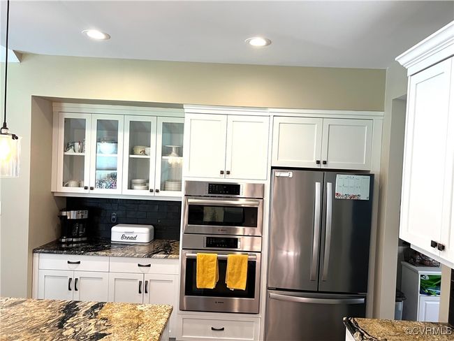 Kitchen featuring stainless steel appliances, granite countertops, glass insert cabinets, white cabinetry, and recessed lighting | Image 5