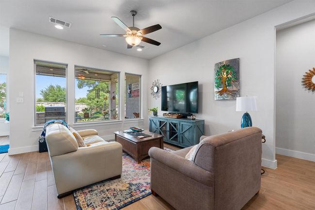 Living room featuring healthy amount of natural light, a ceiling fan, wood finished floors, baseboards, and recessed lighting | Image 8