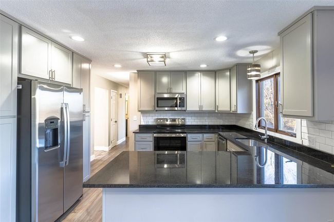Kitchen with sink, light hardwood / wood-style flooring, kitchen peninsula, decorative light fixtures, and appliances with stainless steel finishes | Image 38