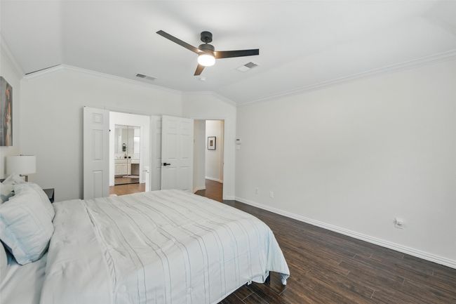 Bedroom featuring vaulted ceiling, crown molding, dark wood-style floors, and a ceiling fan | Image 19