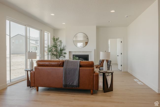 Living room featuring light wood-type flooring, a fireplace, baseboards, and recessed lighting | Image 10