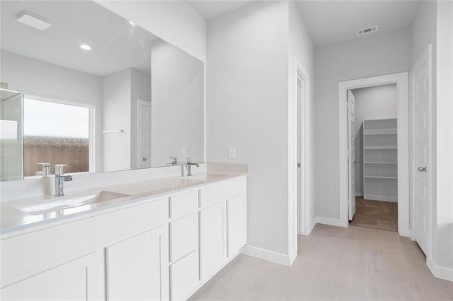 This primary bathroom is definitely move-in ready! Featuring stained cabinets with light countertops and dual sinks, spacious walk-in closet with shelving, high ceilings, custom paint, sleek fixures, and modern finishes. | Image 11