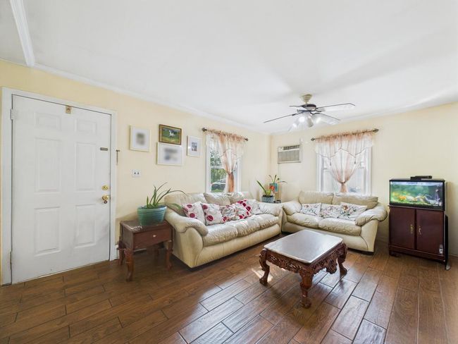 Living area featuring hardwood / wood-style flooring, ceiling fan, and an AC wall unit | Image 10