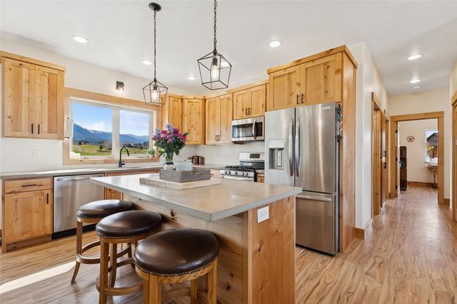 Kitchen with a center island, light countertops, a sink, stainless steel appliances, and a breakfast bar area | Image 22