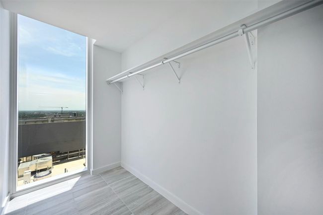Bright and spacious walk-in closet with floor-to-ceiling window, offering natural light and skyline views—perfect for a stylish start to the day. | Image 10