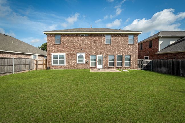 Rear view of house with brick siding, a fenced backyard, and a patio | Image 27