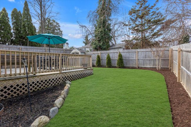 View of back yard fully fenced in featuring a wooden deck. | Image 18