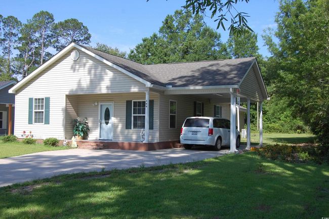 View of front of home with driveway, a carport, a front lawn, and roof with shingles | Image 25