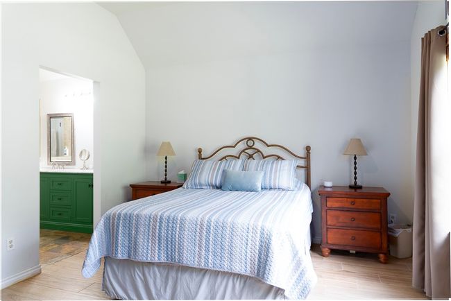 Bedroom featuring lofted ceiling, light wood-style floors, and ensuite bathroom | Image 13