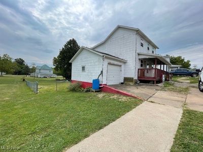 View of side of property featuring a garage, a yard, and a porch | Image 2