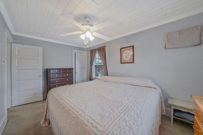 Bedroom with ceiling fan, crown molding, wood ceiling, and carpet flooring | Image 16