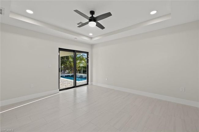Spare room featuring light tile patterned flooring, ceiling fan, and a tray ceiling | Image 24