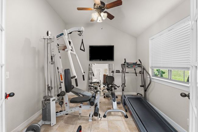 Exercise room featuring a ceiling fan, vaulted ceiling, tile patterned flooring, and baseboards | Image 14