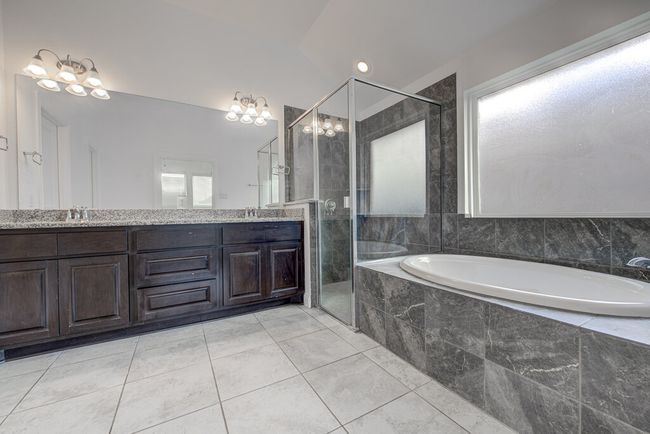 Bathroom with a garden tub, double vanity, a shower stall, vaulted ceiling, and tile patterned flooring | Image 14